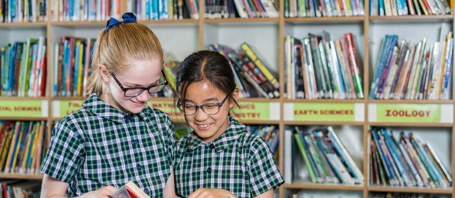 2 girls reading a book together